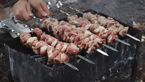 женщина вручную жарит сырое мясо на гриле. приготовление мяса барбекю на угольном гриле