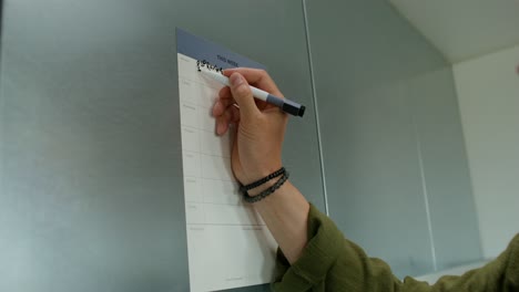 person writing on a weekly planner