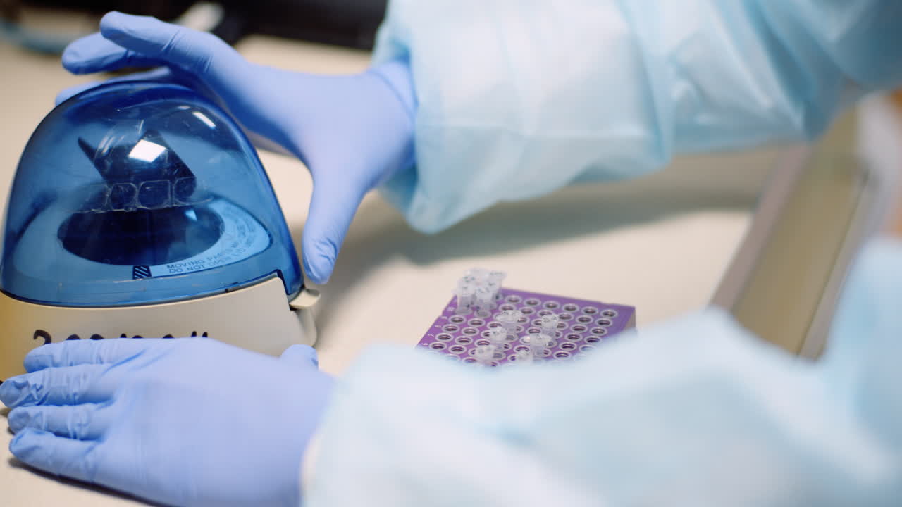 Scientist Putting Test Tubes With Bacteria In Shaker At Laboratory