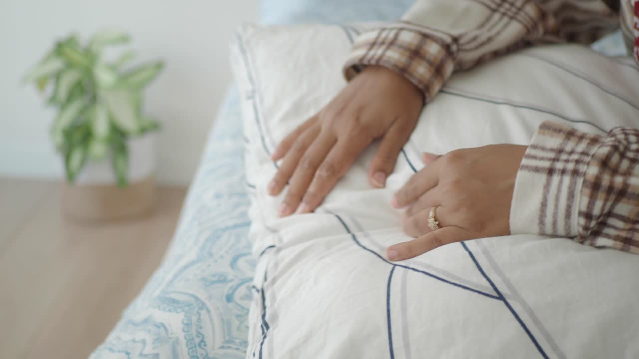 Woman resting on a bed with hands on pillow