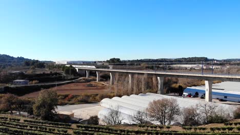 Antena:-Tren-De-Alta-Velocidad-Cruzando-Un-Viaducto-En-España,-Entre-Barcelona-Y-Madrid