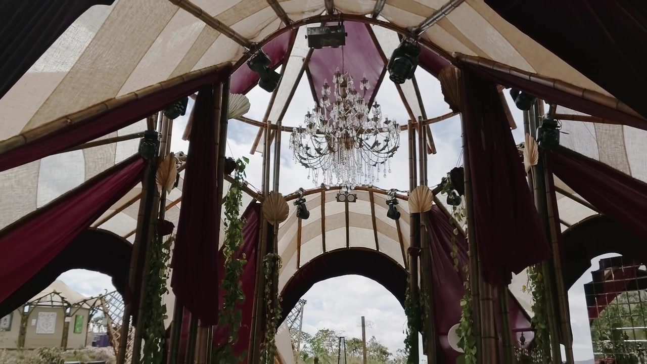 Intérieur de pavillon artisanal avec des lustres métalliques ornementaux, un toit en tissu translucide et une végétation décorative dans le Parc National de la Chapada dos Veadeiros, Goias, Brésil, révélant une entrée ouverte.