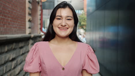 woman smiling in a pink dress in an alley