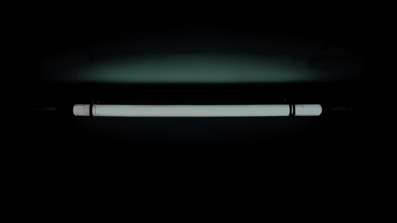 страшная неоновая световая трубка высоко на потолке темного подвала, излучая жуткое свечение