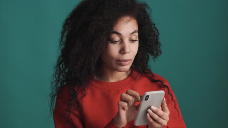 african american woman using smartphone over blue background.