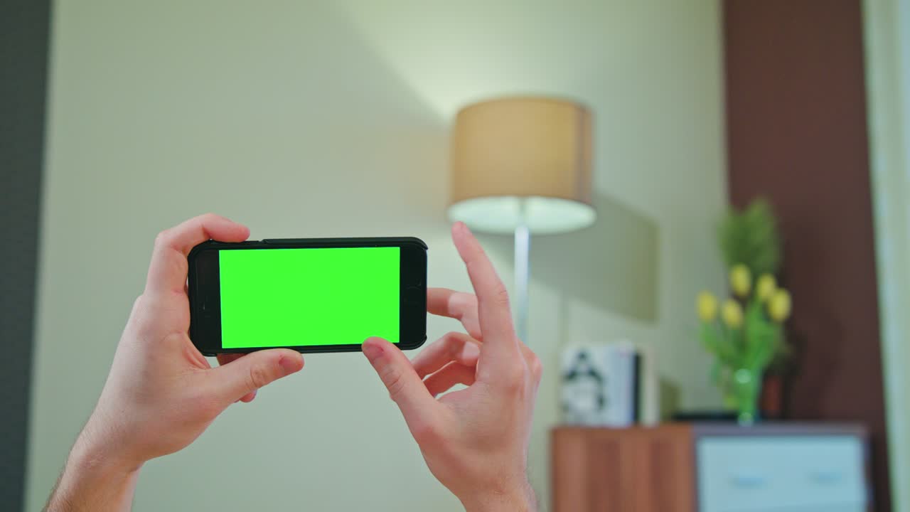 초록색 화면 을 가진 전화 를 들고 있는 남성 의 손