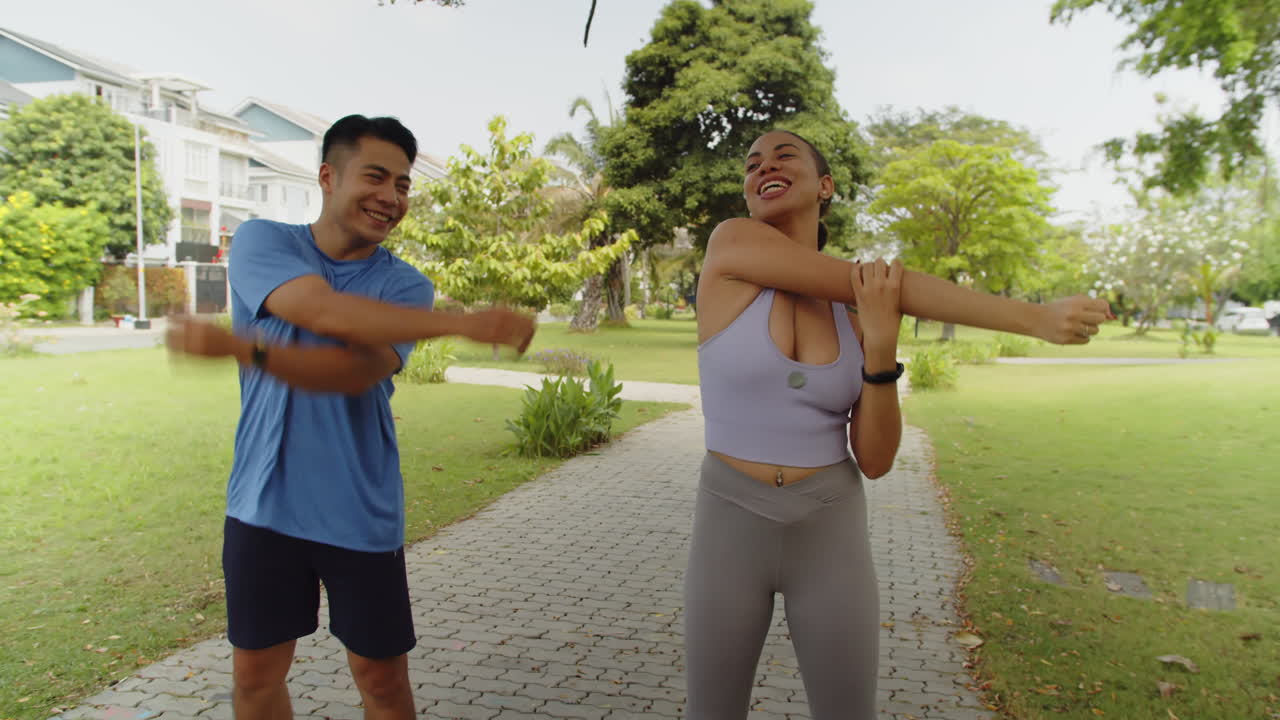 Intercultural Man and Woman Practicing Stretching Exercises in City Park