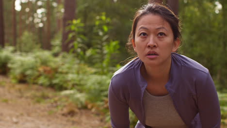 tired mid adult woman exercising doing work out outdoors running along track through forest stopping to catch breath shot in real time 2