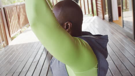 senior african american man enjoys yoga in a log cabin, meditating in slow motion