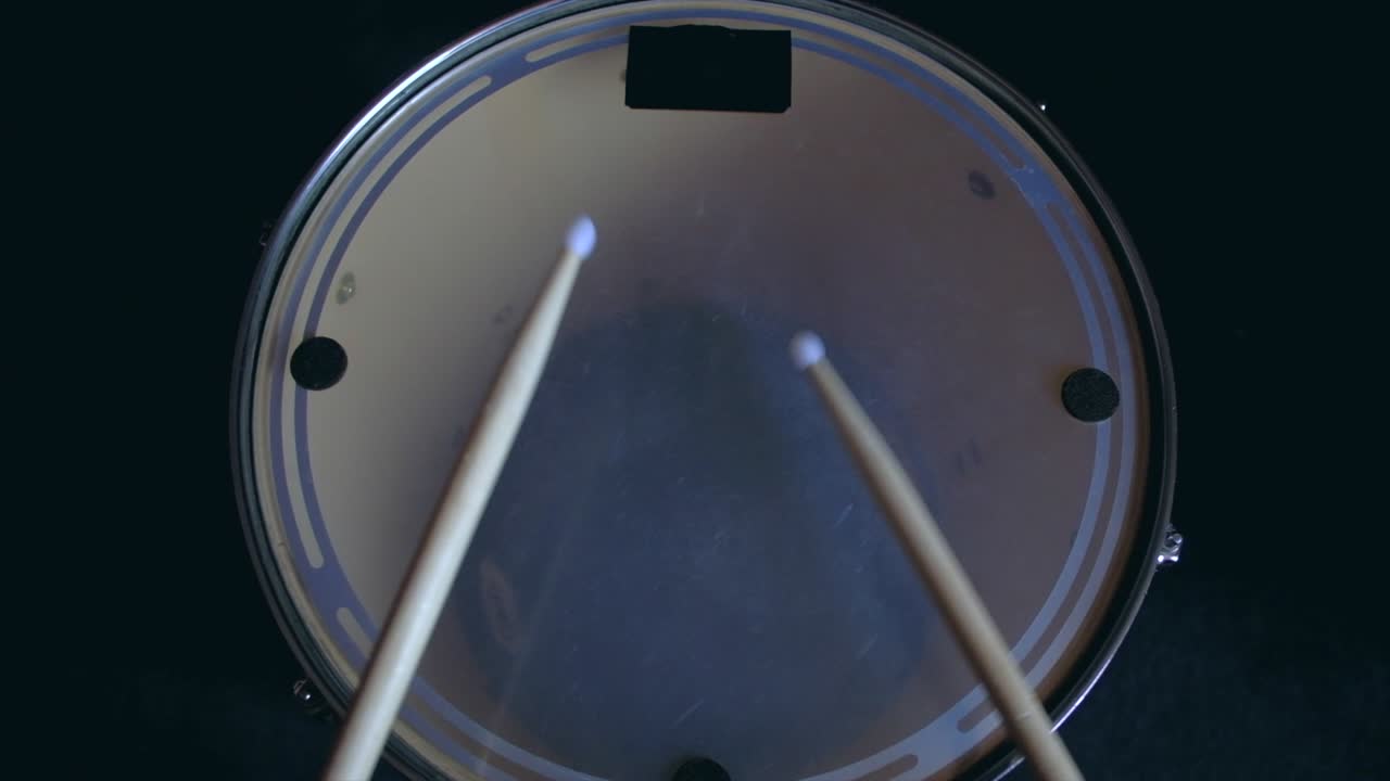 el baterista toca palos de ritmo activo en un tambor de bajo tom, entrenamiento de lección en casa