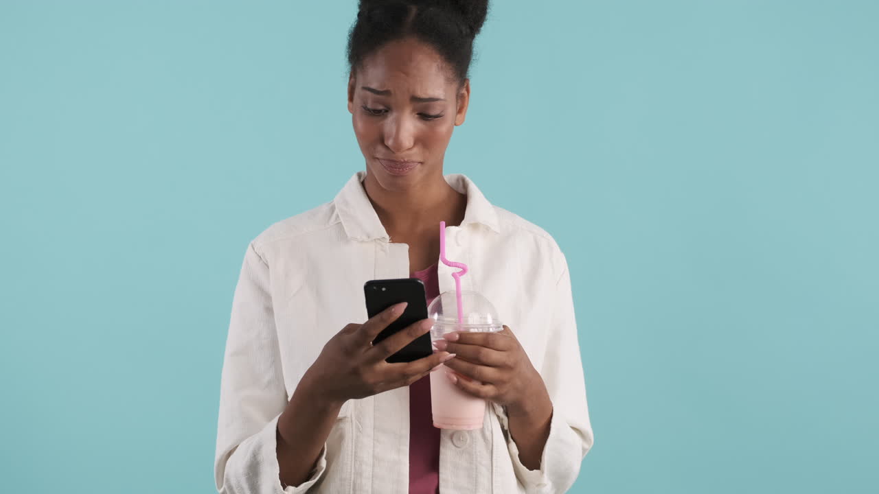Woman drinking milkshake and using phone