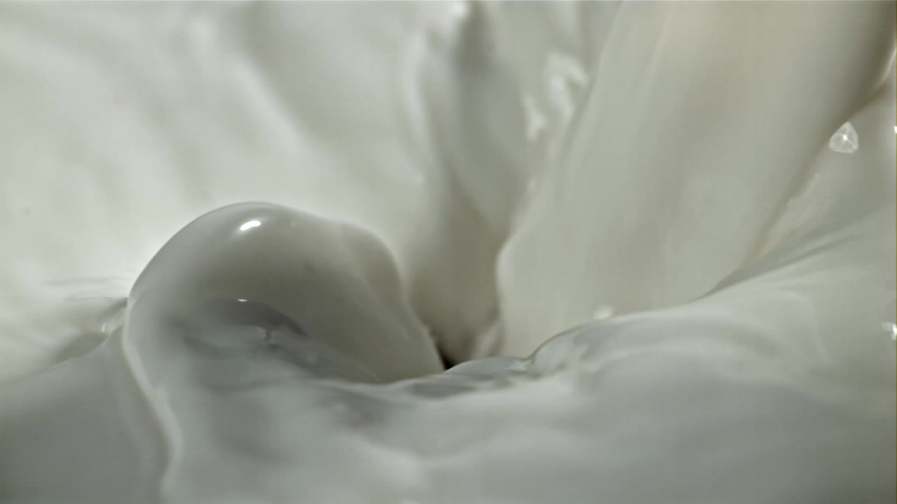 Gros plan au ralenti de lait frais se versant et tourbillonnant