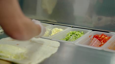 cu cook prepares shawarma adds fresh cucumbers tomatoes onions to the cake with mayonnaise