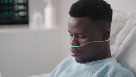 African-Male-patient-using-smart-phone-while-lying-on-bed.-African-patient-having-phone-conversation-in-hospital-room