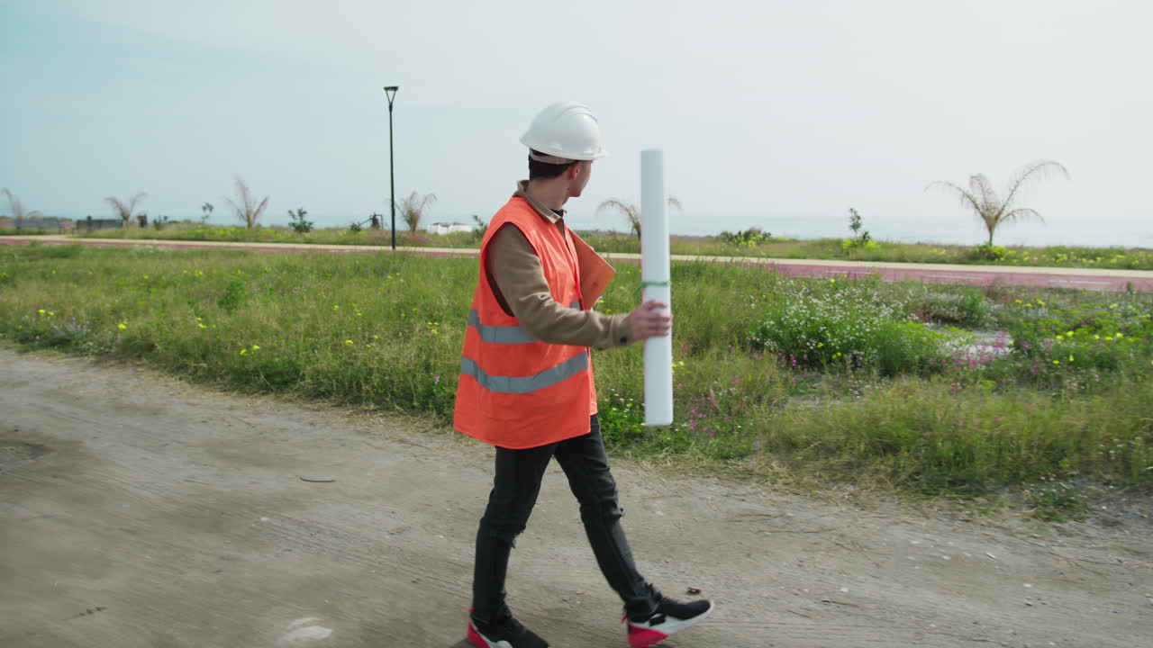 Architect Walking On The Construction Site With The Map In His Hands