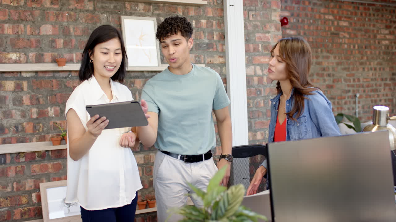 Discussing interior design ideas, multiracial colleagues reviewing tablet in modern office