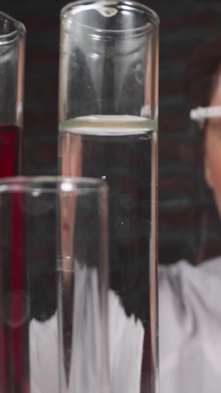 Squinting female researcher with goggles drips catalyzer into test tube in hospital lab slow motion. Probe lens shot of scientist work closeup