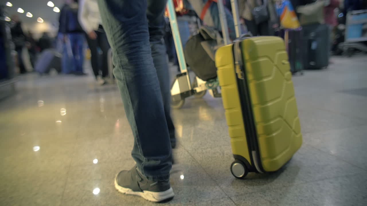 hombre tomando bolsa rodante y caminando lejos en el aeropuerto