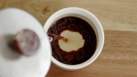 tea is being poured into a cup on a table in daylight