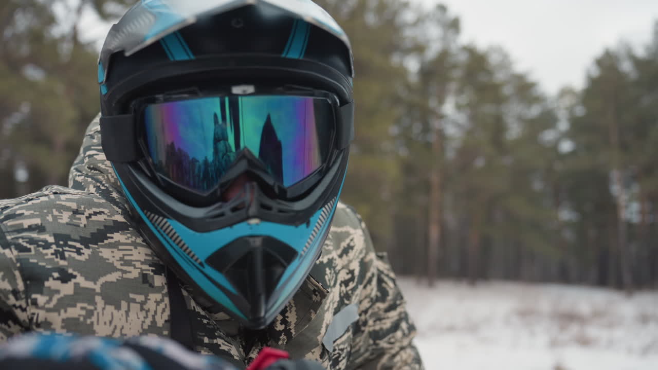 Closeup atv helmet reflection snowy forest mirrored visor reflecting pine landscape rider adjusting strap camouflage jacket texture visible windshield edge quiet anticipation before acceleration