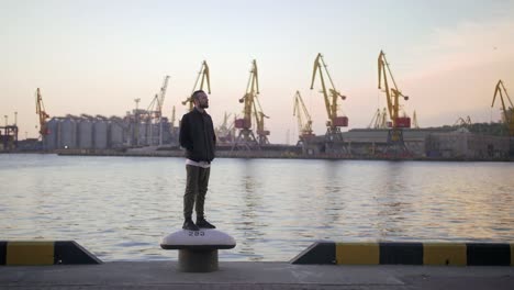 stylish hipster man on sea port background during sunset, looking aside