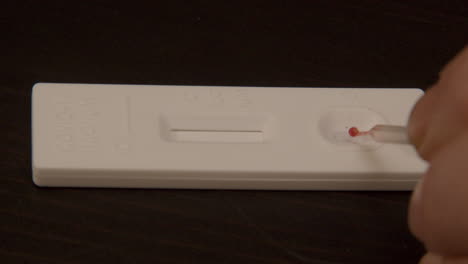 pipette placing drop of blood on covid-19 rapid self test - close