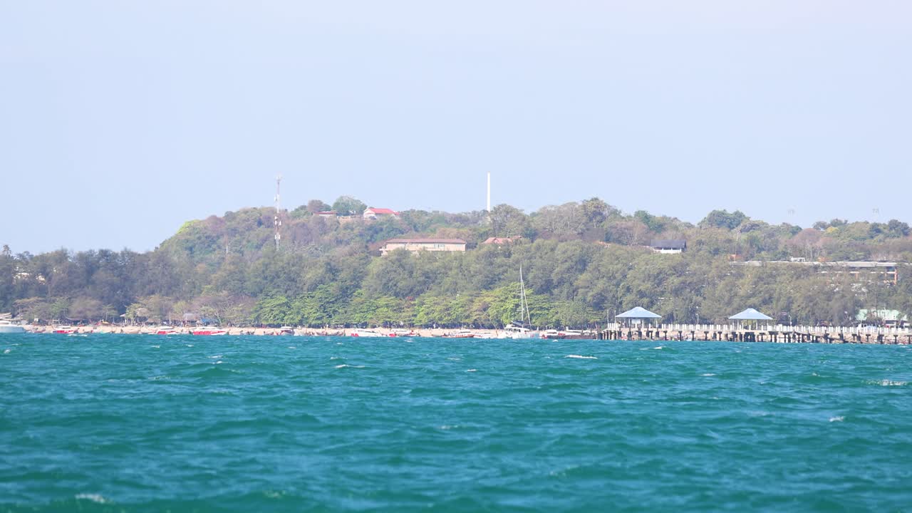 A tranquil ocean scene in Phuket, Thailand, showcasing lush greenery and calm waters under clear daylight, captured with smooth camera movement