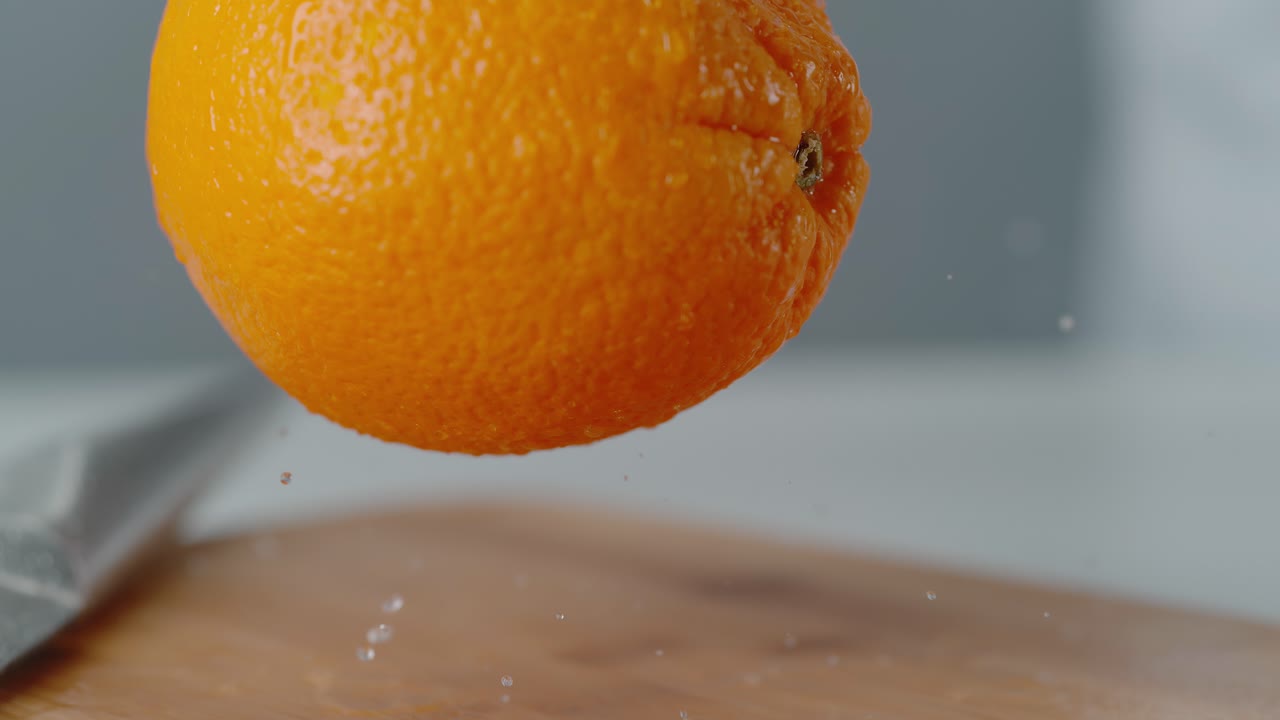 naranja cayendo en la tabla de cortar rebotando con gotas de agua