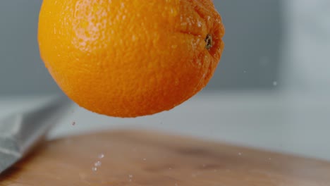 Naranja-Cayendo-Sobre-Una-Tabla-De-Cortar-Rebotando-Con-Gotas-De-Agua