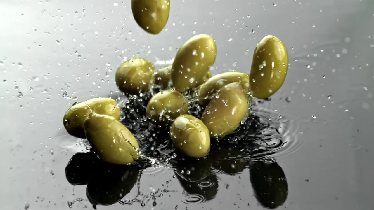Olive verdi fresche che schizzano nell'acqua al rallentatore