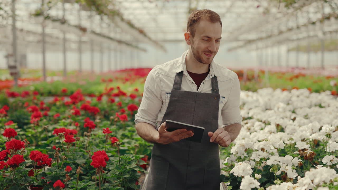 Uomo che lavora in una serra di fiori con un tablet
