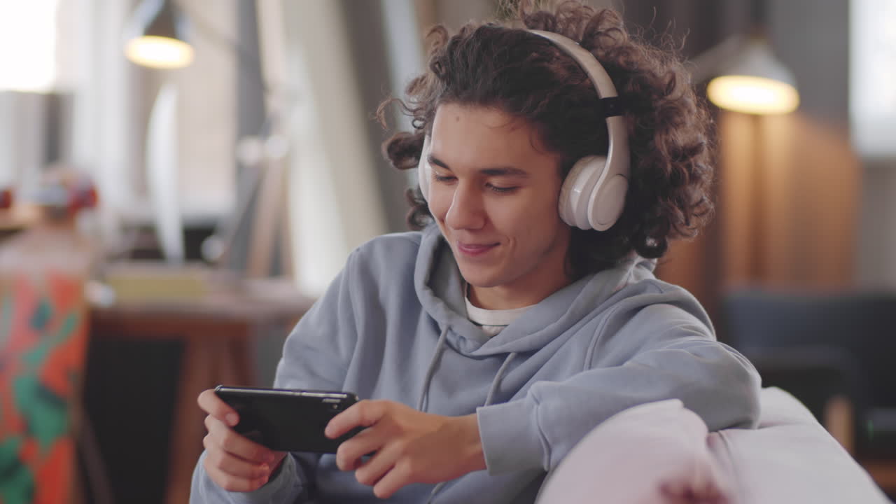 un adolescente alegre jugando a un juego en su teléfono inteligente