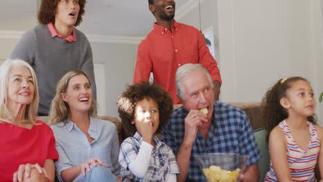 Video-Einer-Gemischten-Familie,-Die-Auf-Der-Couch-Sitzt-Und-Ein-Fußballspiel-Verfolgt