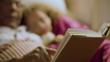 ederly man reading fairy tale for his granddaughter good night