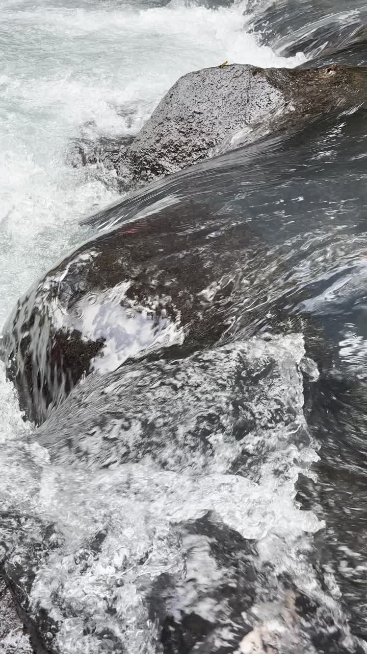 Primo piano dinamico di acqua che scorre sulle rocce in un fiume