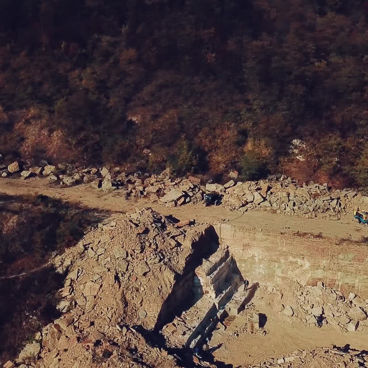 people are walking near sand quarry with the stones below. View of the quarry with the forest. Camera motion up