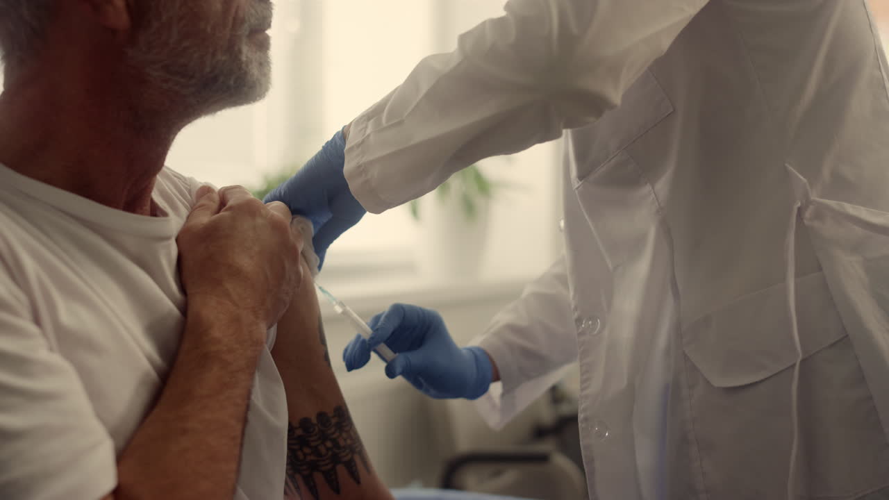 Mature patient getting vaccine dose in clinic closeup. Doctor vaccinating man.