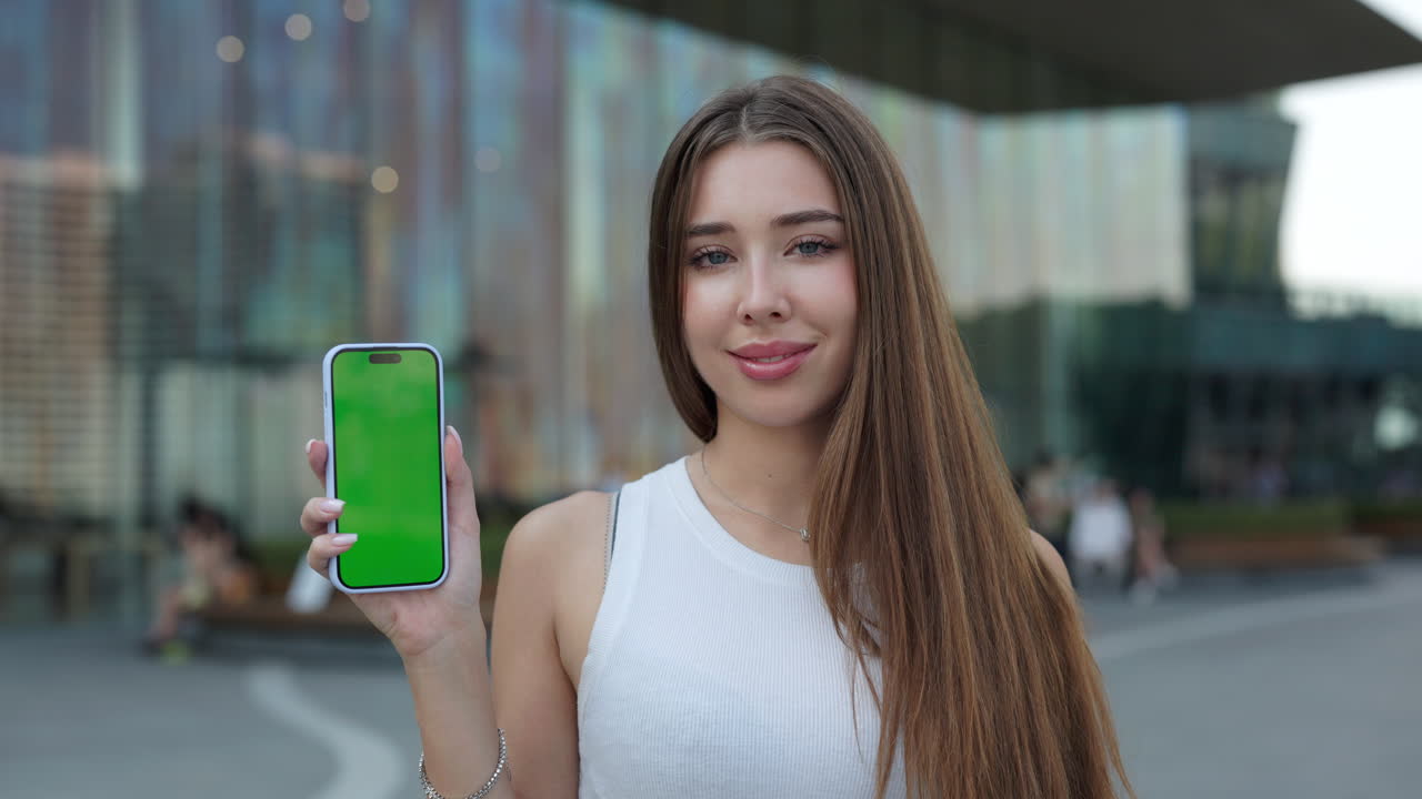mujer sosteniendo un teléfono con una pantalla verde