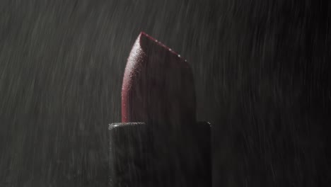 close-up of a red lipstick in the dark with particles