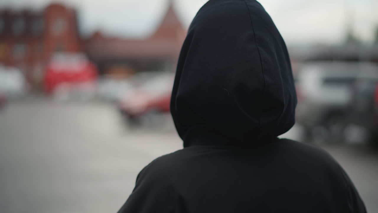 Cena noturna mostrando menina com trança e capuz. Mulher com penteado trançado de costas em ambiente urbano à noite. Vista traseira de jovem mulher com trança e capuz em ambiente noturno da cidade.