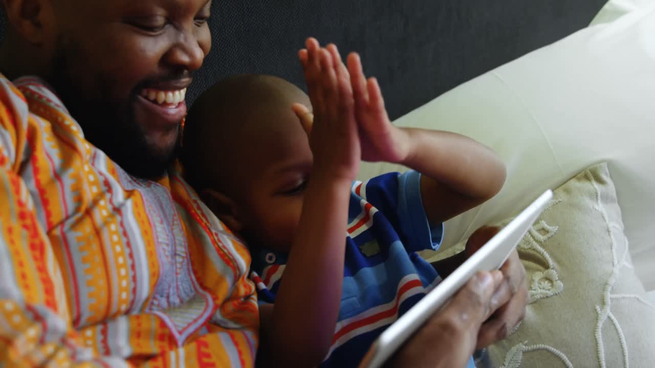 padre e hijo usando tableta digital en la cama en casa 4k