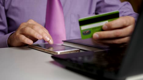 un hombre de negocios con una camisa púrpura y corbata está haciendo un pago a la banca por internet. compras en línea con tarjeta de crédito en el teléfono inteligente.