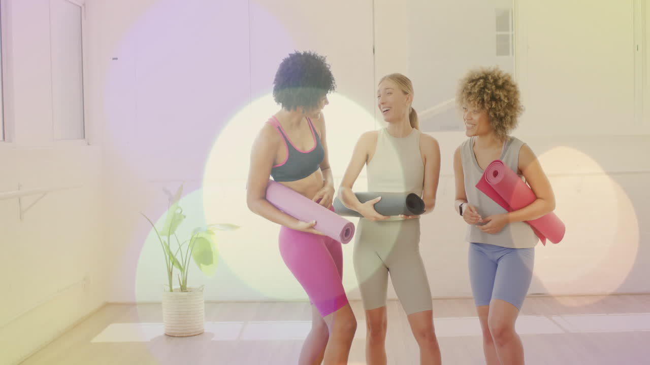 animación bokeh ligera sobre mujeres sosteniendo esteras de yoga y charlando en el estudio