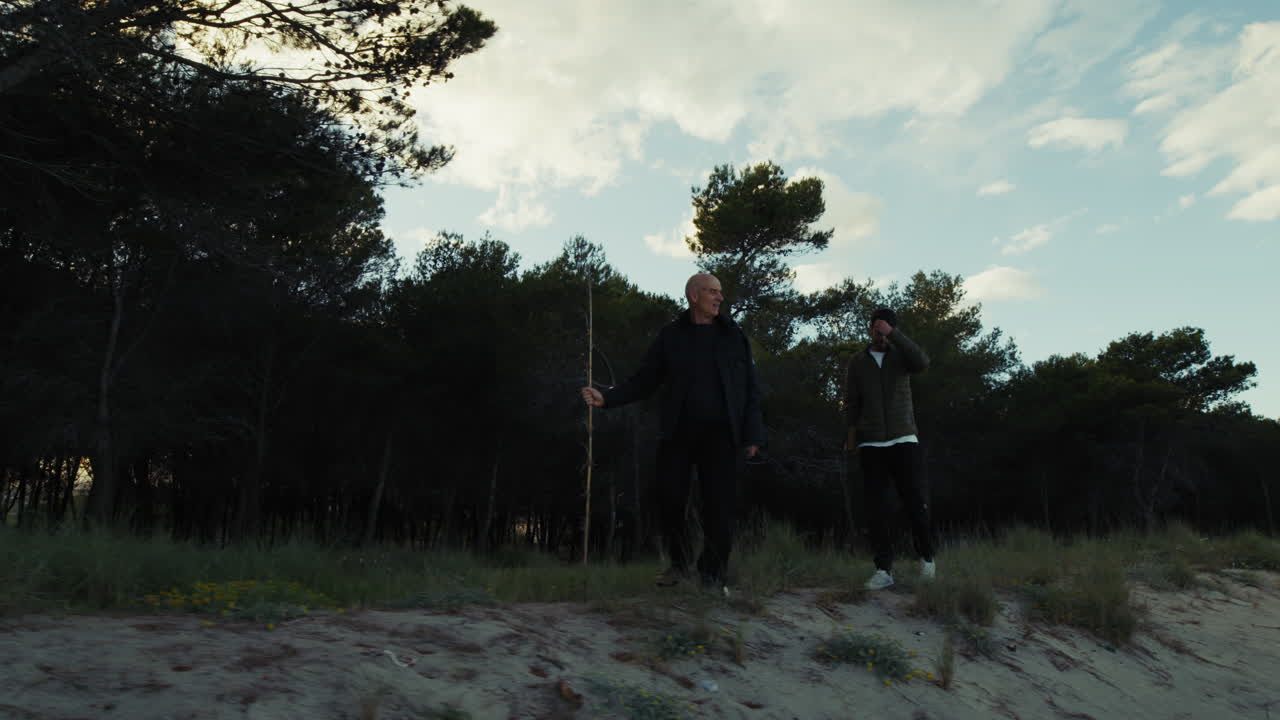 Near a Pine Forest Two Men Walk Along the Beach Path in the Afternoon
