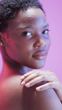 vertical video of african american woman with short dark hair in blue and pink light, slow motion