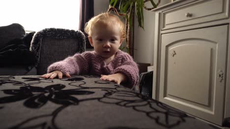 Baby-girl-with-red-hair-and-pink-sweater-taking-her-first-steps