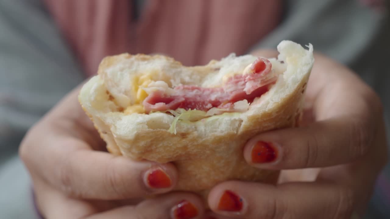 반 먹은 샌드위치를 들고 있는 손