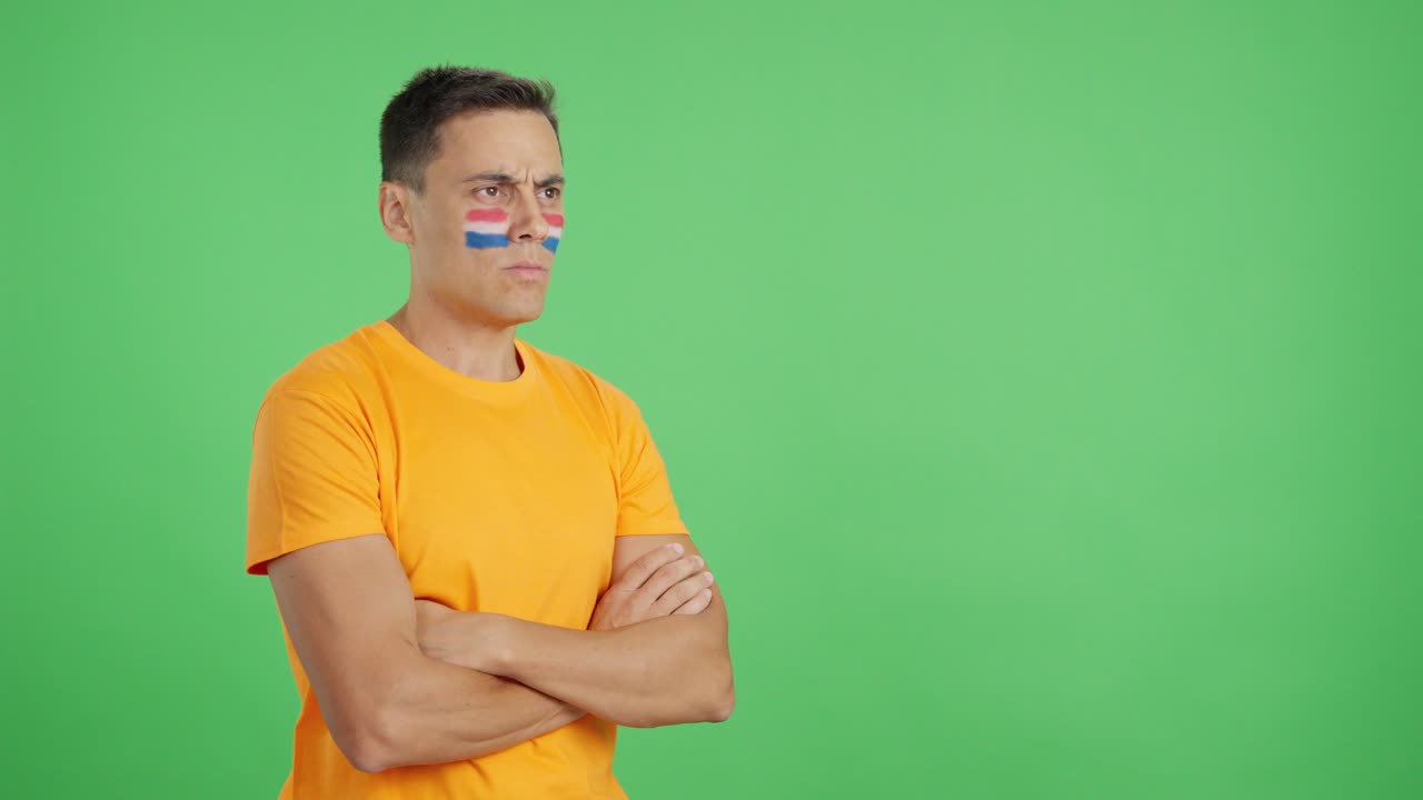 Hombre con la bandera de los Países Bajos pintada mirando hacia otro lado con expresión seria