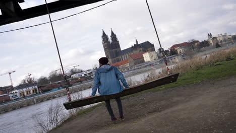 4k slow motion young man on a swing at the elbe riverside in magdeburg, germany