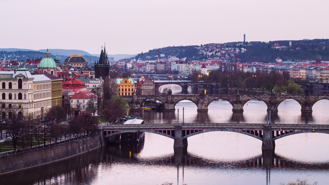 Timelapse del crepuscolo a Praga, accensione dei lampioni su ponti famosi, vista con zoom indietro